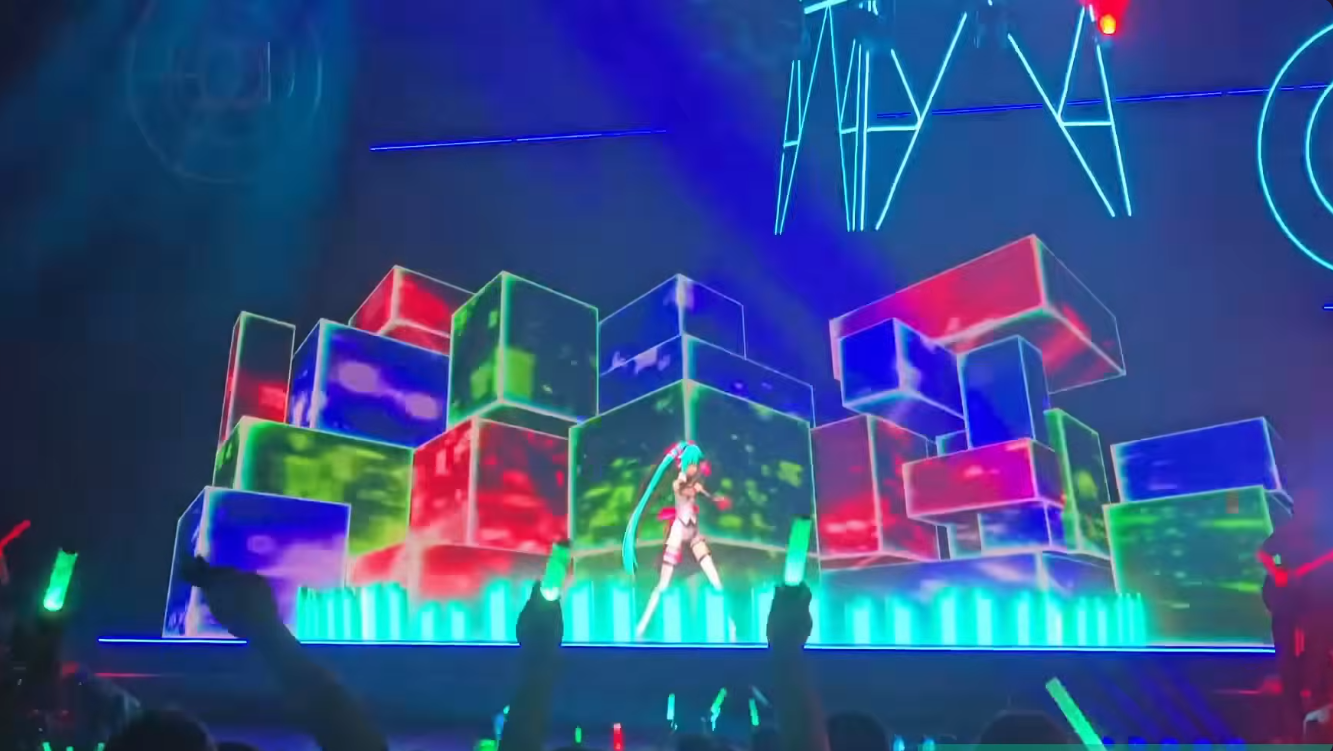 Miku standing inside a wall of glowing blocks drawn on the wide LED screen